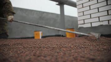 Worker Leveling Expanded Clay on Flat Roof Surface video