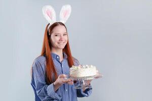 woman wearing rabbit ears holding Easter cake isolated over light gray background, copy space photo