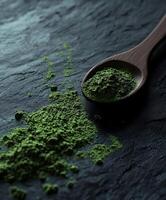 Moringa powder on wooden spoon against dark stone background photo