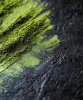Bright green moringa powder spread on a textured dark surface photo