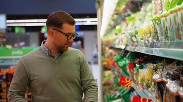 Man selecting fresh salad in grocery store produce aisle video