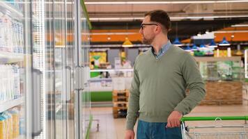 Man selecting milk in grocery store refrigerated aisle video