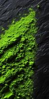 Bright green moringa powder scattered on textured dark surface photo