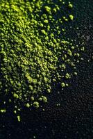 Bright green moringa powder spread on a dark surface photo