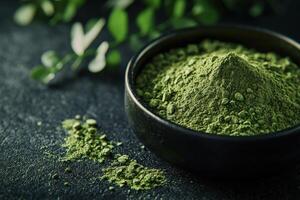 Moringa powder in a bowl with green leaves on a dark surface photo