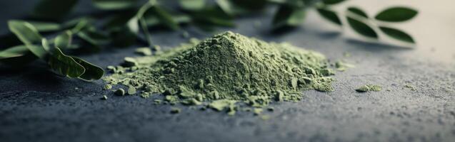 Moringa powder sits atop a dark surface with fresh leaves nearby photo