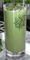 Moringa powder smoothie in a clear glass on a marble countertop photo