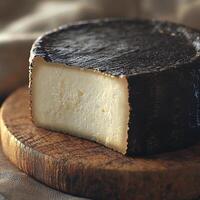 Goat cheese on a wooden board with dark outer rind photo