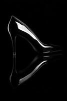 A black high heel shoe with a reflection of the shoe photo