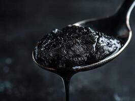 A spoon full of black coal is being poured into a pot photo