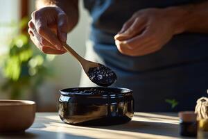 A person is stirring a bowl of black mud photo