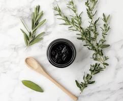 A jar of black clay with herbs and a wooden spoon photo