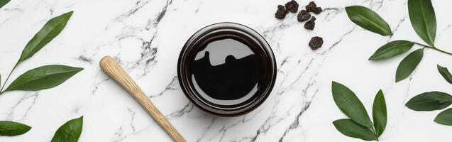 Natural shilajit resin presented with green leaves and a wooden tool photo