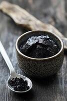 Natural shilajit resin in a bowl with a spoon on wooden surface photo