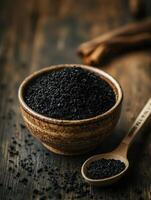 Black cumin seeds in a bowl with a wooden spoon on a wooden table photo
