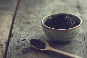 Shilajit powder in a rustic bowl on a wooden surface photo
