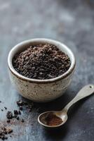 Shilajit powder in a bowl with a spoon on a dark surface photo