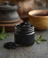 Natural shilajit resin in a glass jar with tea and herbs nearby photo
