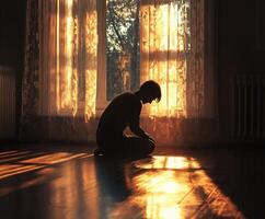 Boy sits in quiet contemplation during sunset in a warm room photo