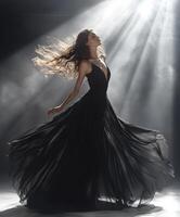 Elegant dancer twirls in a flowing black gown under dramatic lighting photo