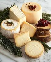 Assorted gourmet cheeses arranged on a marble platter with herbs photo