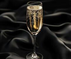 Sparkling champagne in a flute on dark silk fabric photo
