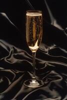 Elegant champagne flute on dark satin backdrop with bubbles photo