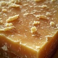 Parmesan cheese block showcasing texture and surface details in a close-up view with grated pieces scattered on top photo