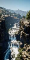 Mountain river cascades between steep cliffs in a serene wilderness setting under clear blue skies photo