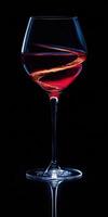 Elegant wine glass with swirling liquid against a dark background creating a striking visual contrast photo