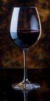 Elegant red wine glass illuminated against a softly blurred background during an evening gathering photo