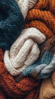 Cozy collection of knitted scarves in various colors and textures displayed on a textured surface photo