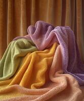 Colorful textured blankets arranged artistically on a draped surface in a warm-toned interior setting photo