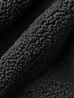 Textured boucle fabric in dark gray displaying its soft, plush qualities, ideal for cozy apparel and home decor projects photo