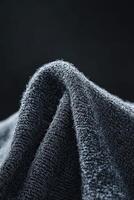 Soft boucle fabric drapes gently against a dark background, showcasing its textured surface and rich details for textile enthusiasts photo