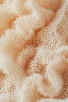 Soft and textured boucle fabric in light peach color showcasing intricate patterns and delicate weave photo