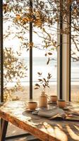 Morning tea on a wooden table by the window with a beach view during golden hour photo