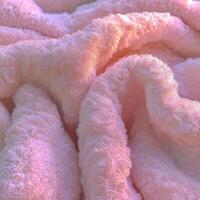 Soft pink boucle fabric texture with gentle waves and folds captured in warm light photo