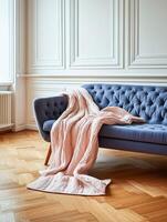 Cozy blue tufted couch with a pink knitted blanket draped over it in a serene living room setting photo