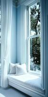 Cozy window nook featuring white cushions and soft curtains with sunlight streaming through in a serene blue room photo