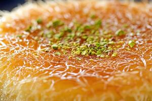 Delicious kunafa dessert topped with crushed pistachios served on a plate during a festive occasion photo