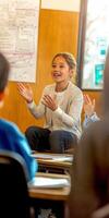 A girl sitting in a classroom with her hands up photo