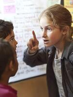 A young girl pointing at a group of children photo