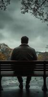 A man sitting on a bench in the rain photo