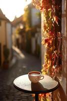 Porcelain coffee cup resting on a table amidst autumn leaves in a quaint cobblestone street photo