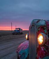 Vintage truck parked on a dusty road during sunset with another truck in the background, showcasing rustic charm and tranquility photo