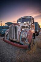 Old trucks parked at sunset in a rural area showcasing weathered paint and historical charm photo