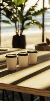 Coffee cups arranged on a sunlit table by the beach photo