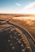 Rolling hills with hay bales at sunset photo