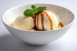Vanilla ice cream scoops with caramel topping and mint leaf in a bowl photo